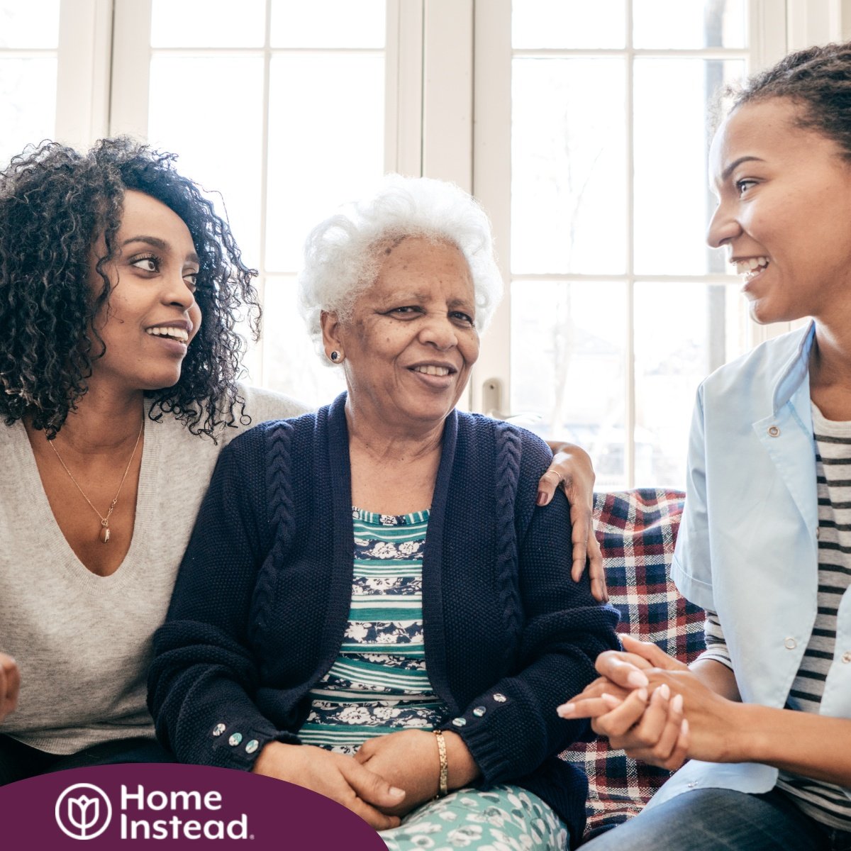 A caregiver talks with a client and her daughter, representing the type of communication that is vital when taking on a person-centered care approach.