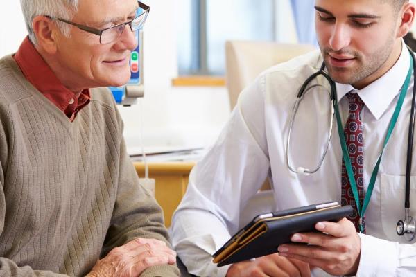 An older man talks with a doctor representing the effective communication that family caregivers should endeavor to have.