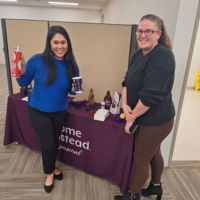 two smiling ladies at home instead's hot cocoa bar booth