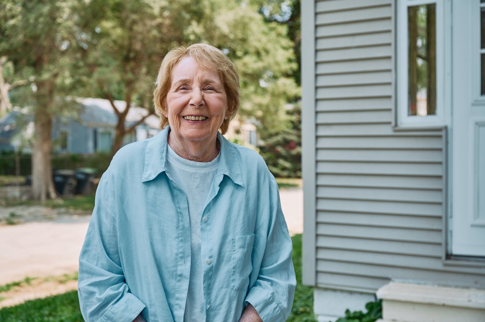 Home Instead Caregiver waters flowers while on back porch with senior client.