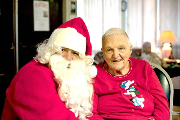 Santa and a senior woman sit smiling together