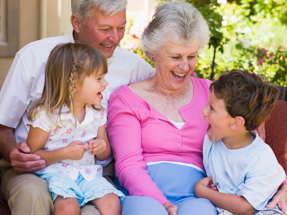 grandparents sat on a sofa laughing with grandchildren HtcAiHRri PMNW