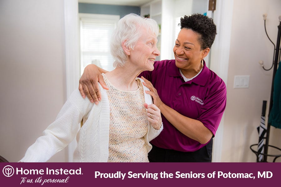 Caregiver helping an elderly woman put on a sweater