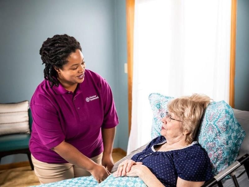 home instead caregiver comforting a senior laying in bed