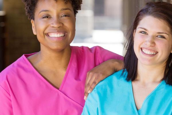 2 smiling women in scrubs represent RN supervisors and the good environment that can be promoted when they work together with caregivers for quality client care.