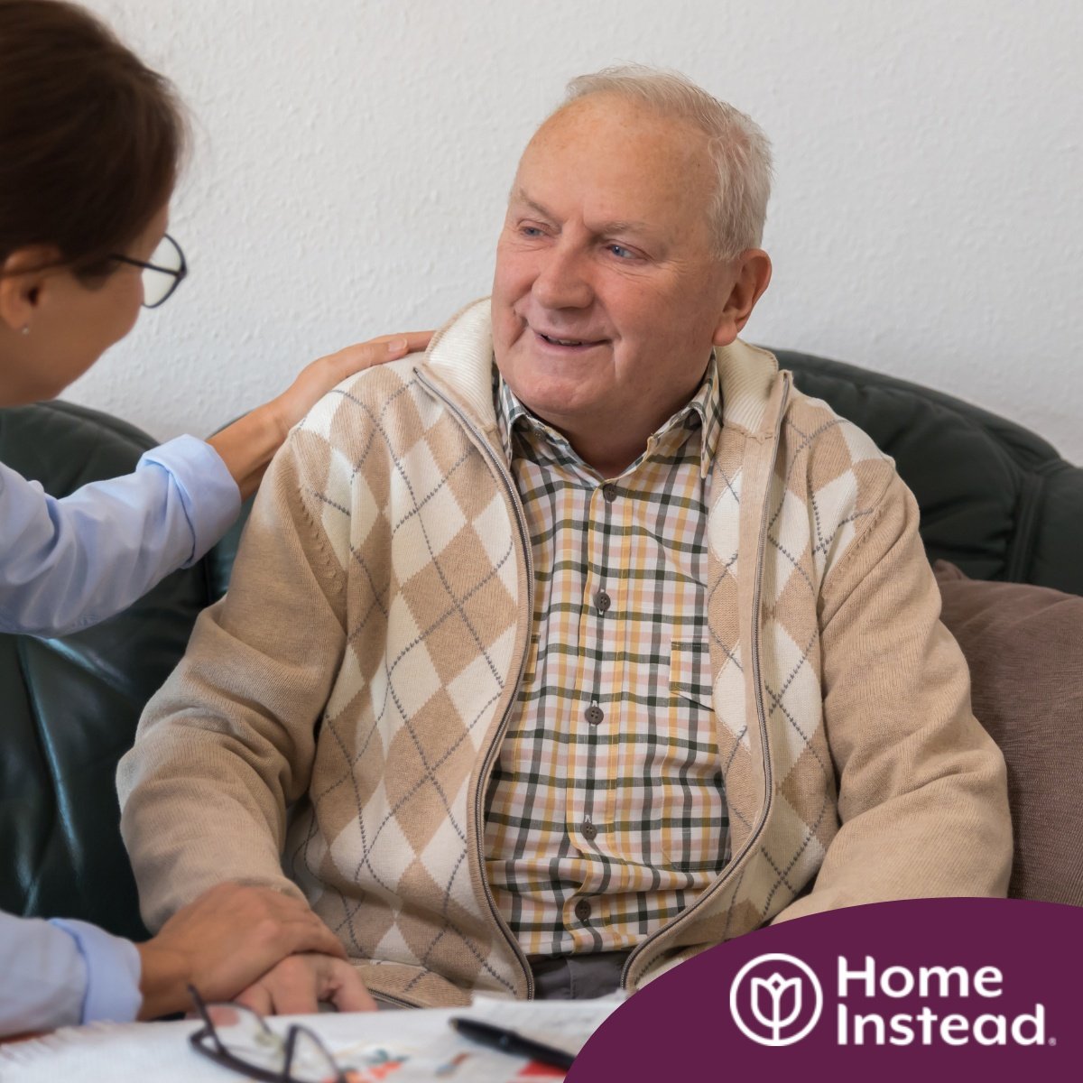 A caregiver compassionately listens to an older man, representing the kind of patience and empathy that help with communicating with clients who have dementia.