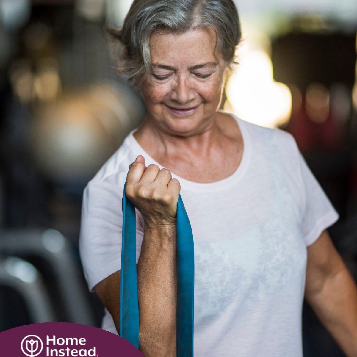 An older woman uses a resistance band to exercise, representing how staying active can help older adults keep their blood pressure in a healthy range.