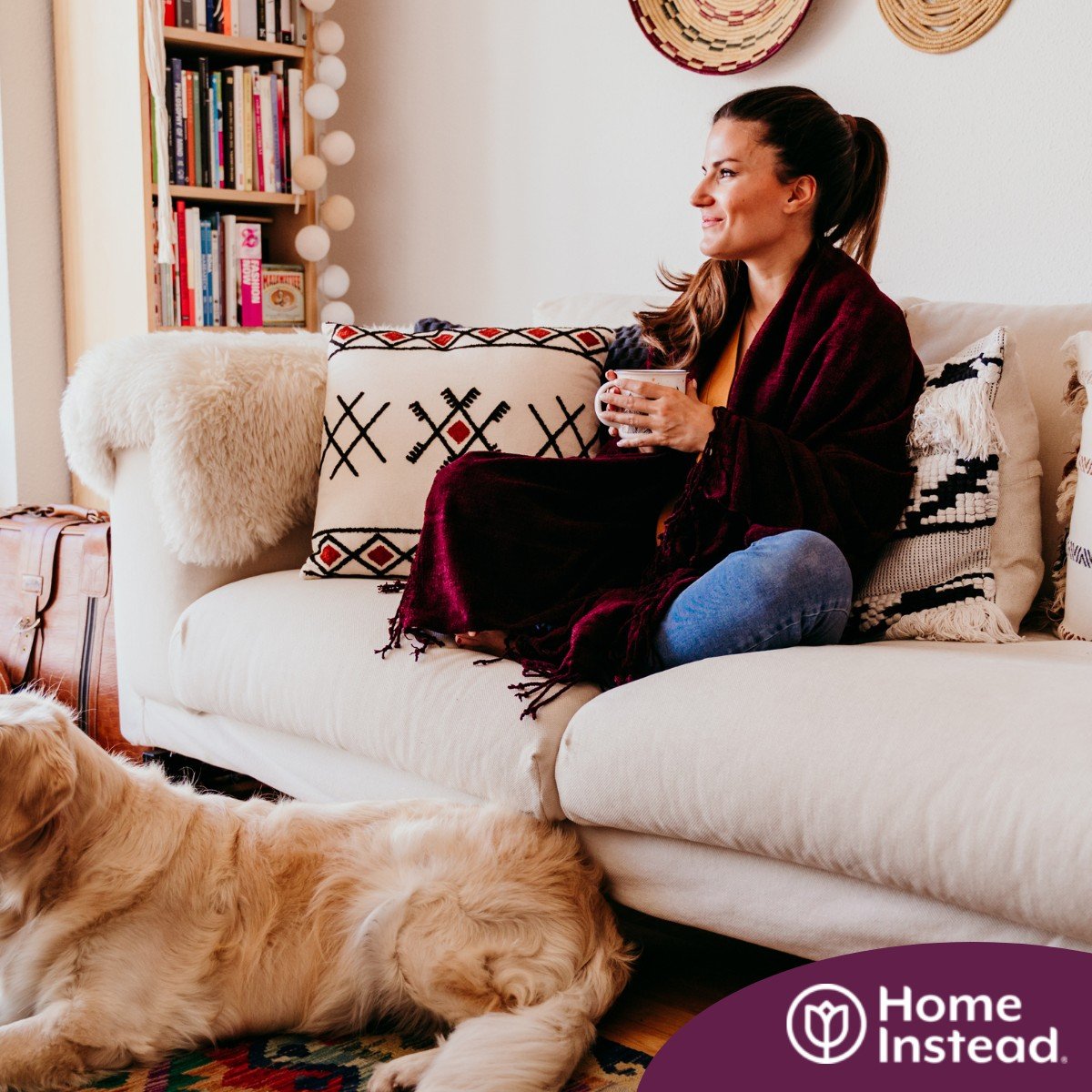 A woman relaxes with her dog while sipping on tea, representing how self-care can combat caregiver stress.