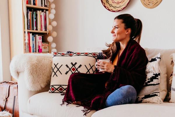 A woman relaxes with her dog while sipping on tea, representing how self-care can combat caregiver stress.