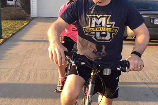 Husband & wife on a tandem bike in front of their garage