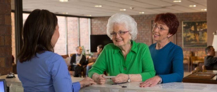 caregiver helping senior check in at front desk