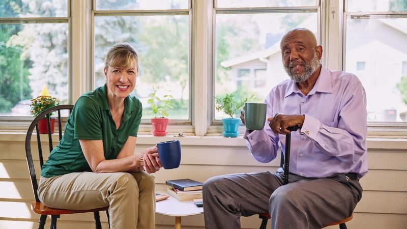 Home Instead caregiver and client holding mugs at a kitchen table in Deer Valley Estates, Peoria Arizona