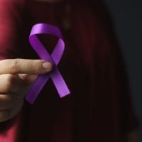 womans hand holding purple ribbon