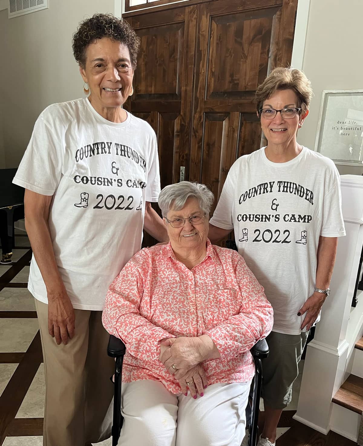 two caregivers stand next to their client in a wheelchair