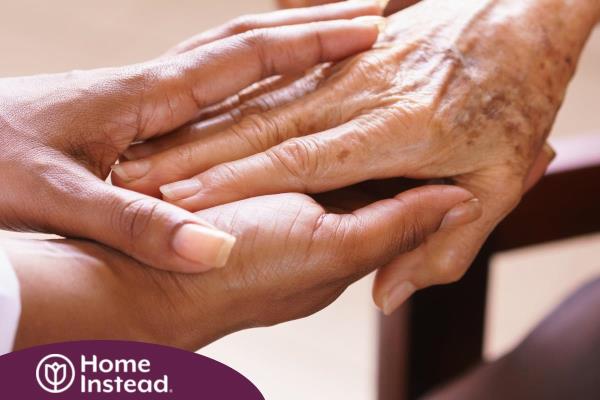 A pair of younger hands hold older ones, representing the compassionate care that a professional caregiver can provide.