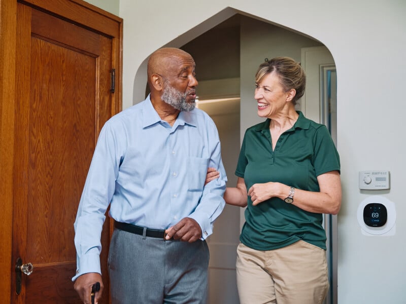 Home Instead Care Pro and aging man standing in doorway.