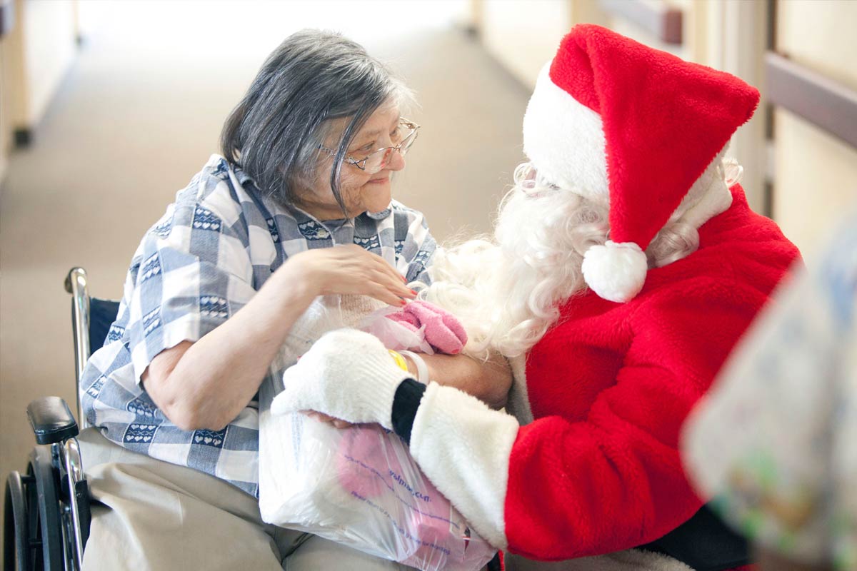 Santa shares a holiday gift with a grateful elderly woman