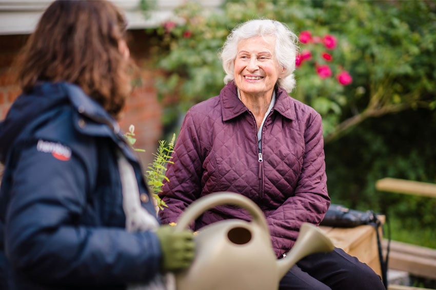 Senior woman talking with young woman while gardening