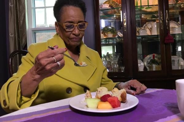 Senior woman sitting at dining room table eating healthy meal.