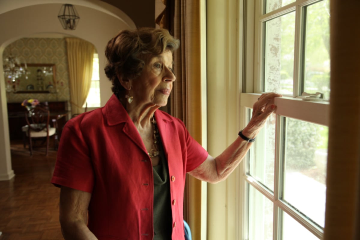 Senior looking out the window in their living room