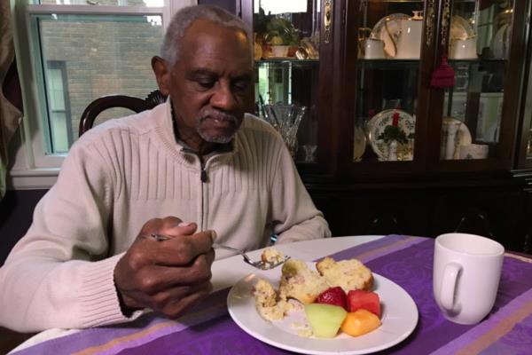 Aging man sitting at dining room table eating healthy meal.