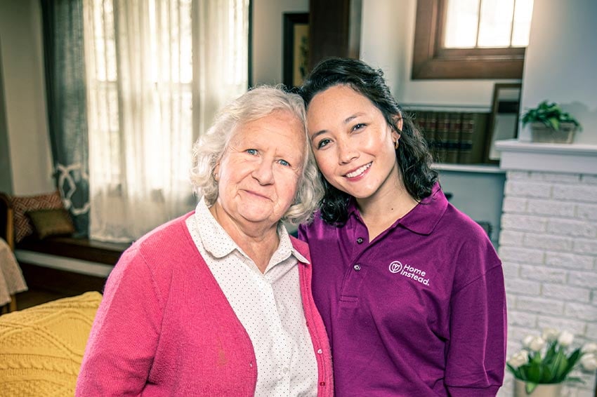 Home Instead caregiver with aging adult looking at camera smiling