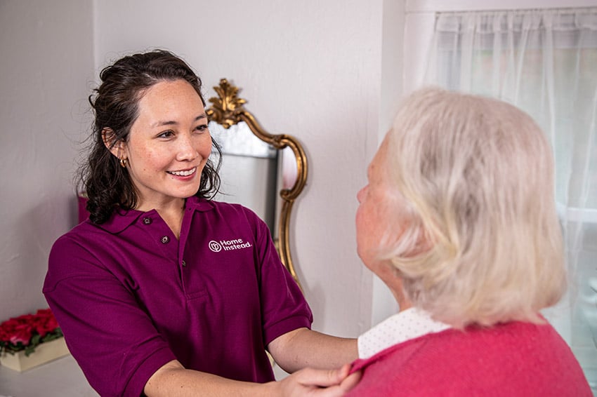 Home Instead CAREGiver helping senior with shirt buttons