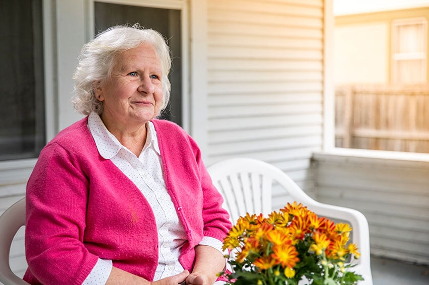 Home Instead Senior sitting outside staring contently with a smile