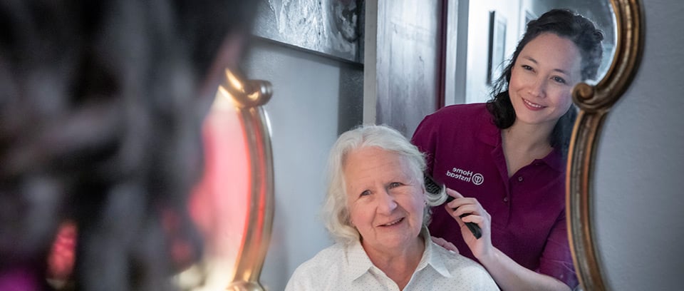 Home Instead Caregiver brushes senior woman's hair at home