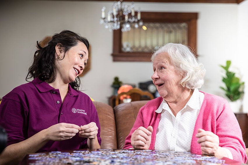 Home Instead Caregiver wearing mask brings groceries to the home of an aging adult.