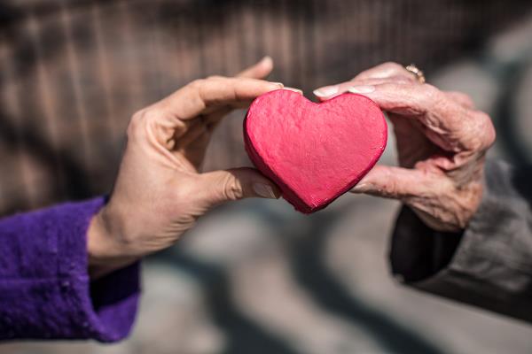 Two hands holding red heart